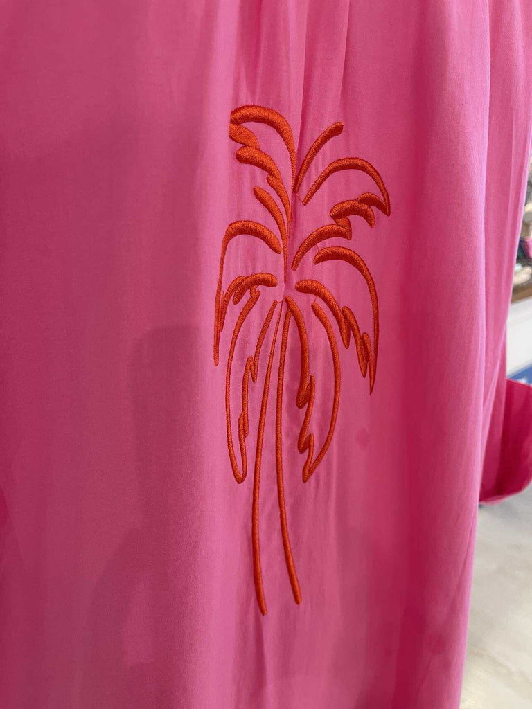 Pink fabric with a red palm tree design on a blurred background