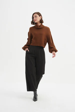 With a refined turtle neck, voluminous sleeves with discreet slits, and a flattering cropped length, it strikes the perfect balance between structure and softness