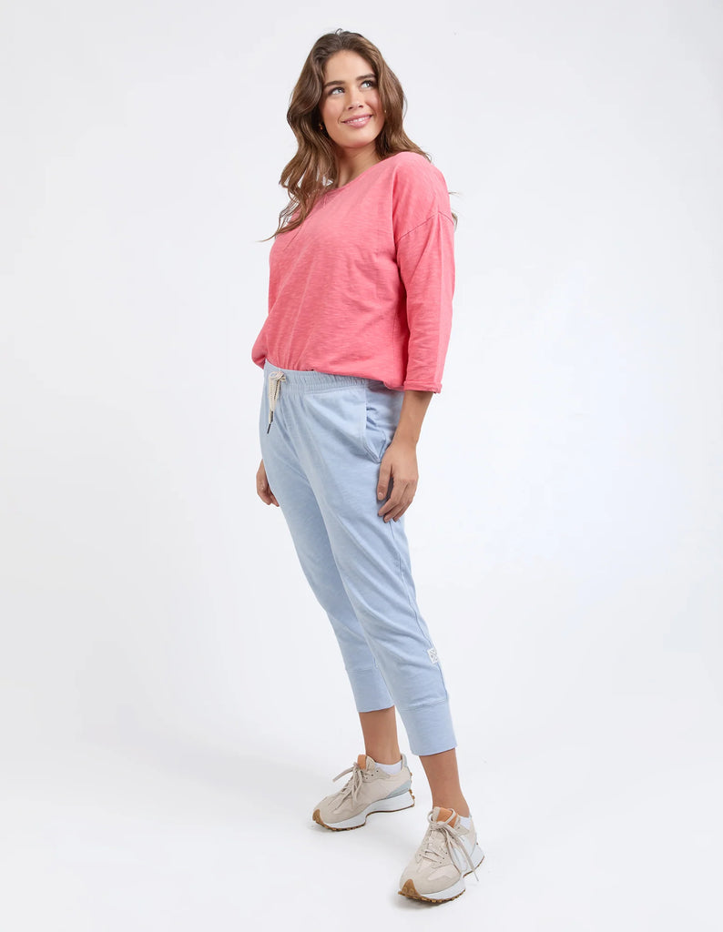 Woman wearing a pink top and light blue pants on a white background