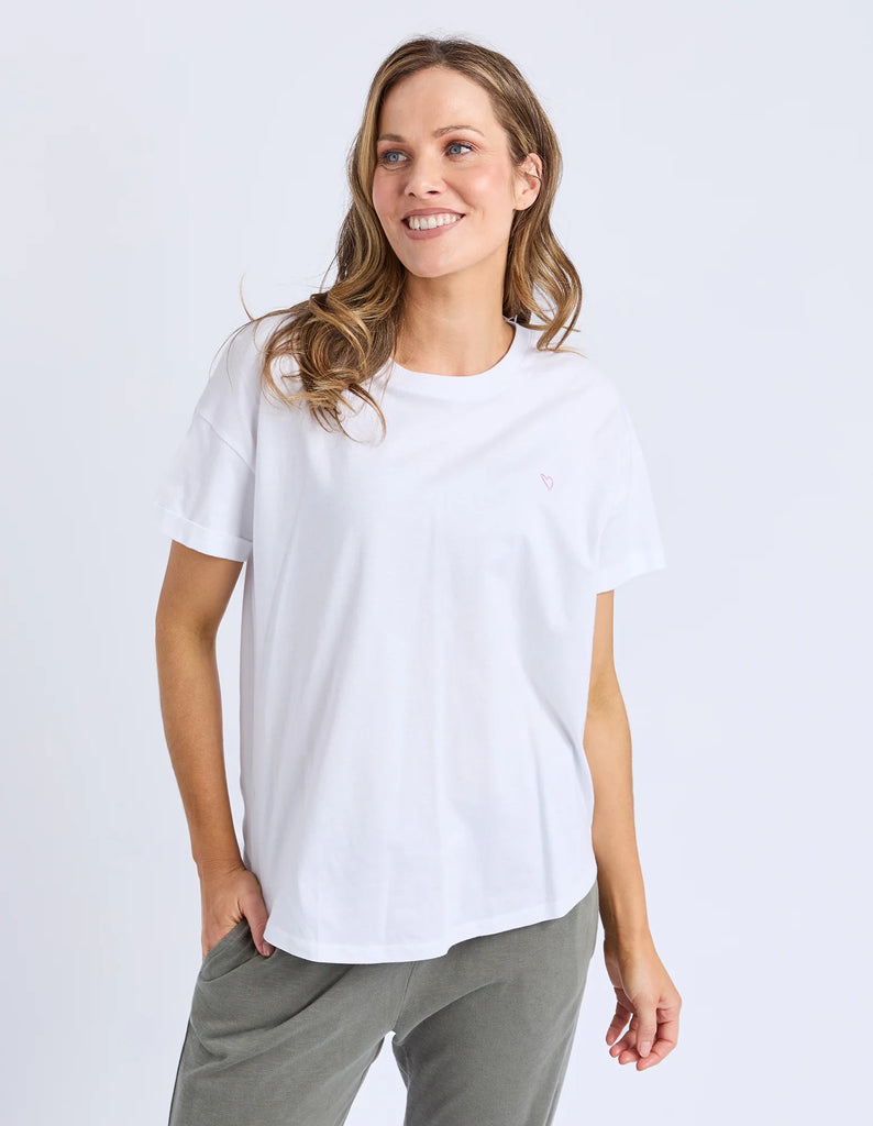 Woman wearing a white t-shirt and gray pants on a light gray background
