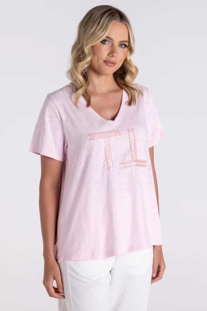 Woman wearing a light pink t-shirt with a logo on a white background