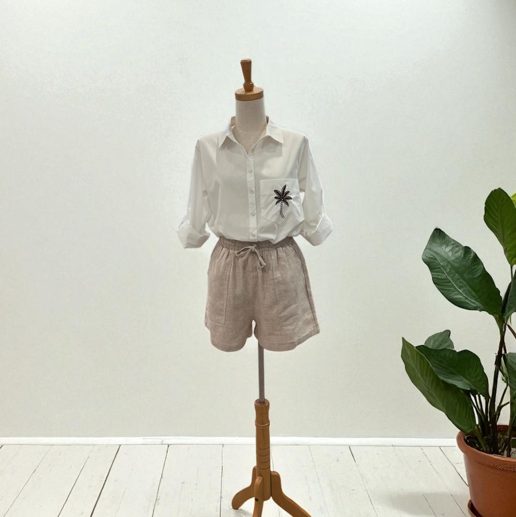 Mannequin wearing a white shirt with a pocket design and beige shorts, standing against a plain background.