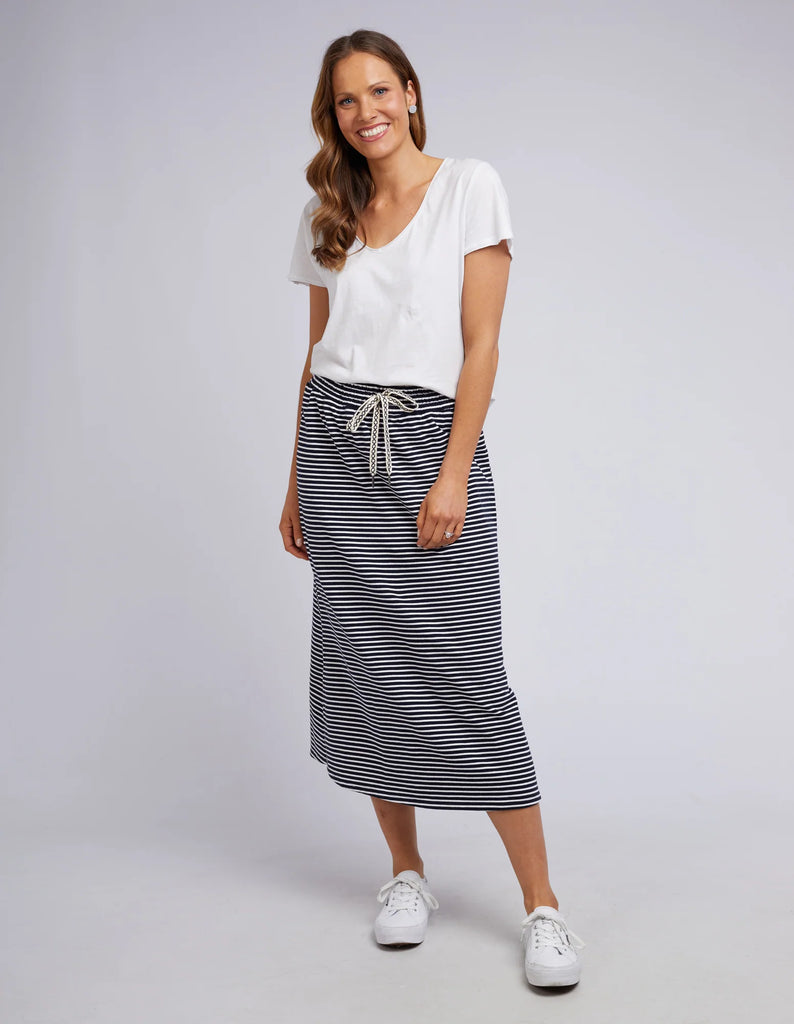 Woman wearing a white top and striped skirt on a plain background