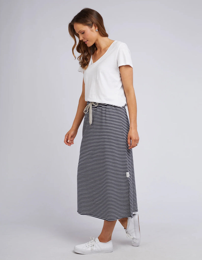 Woman wearing a white top and striped skirt on a plain background