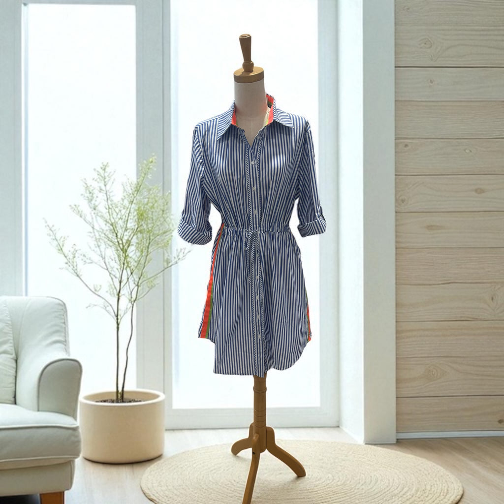 Blue and white striped dress on a mannequin in a room with a couch and plant.