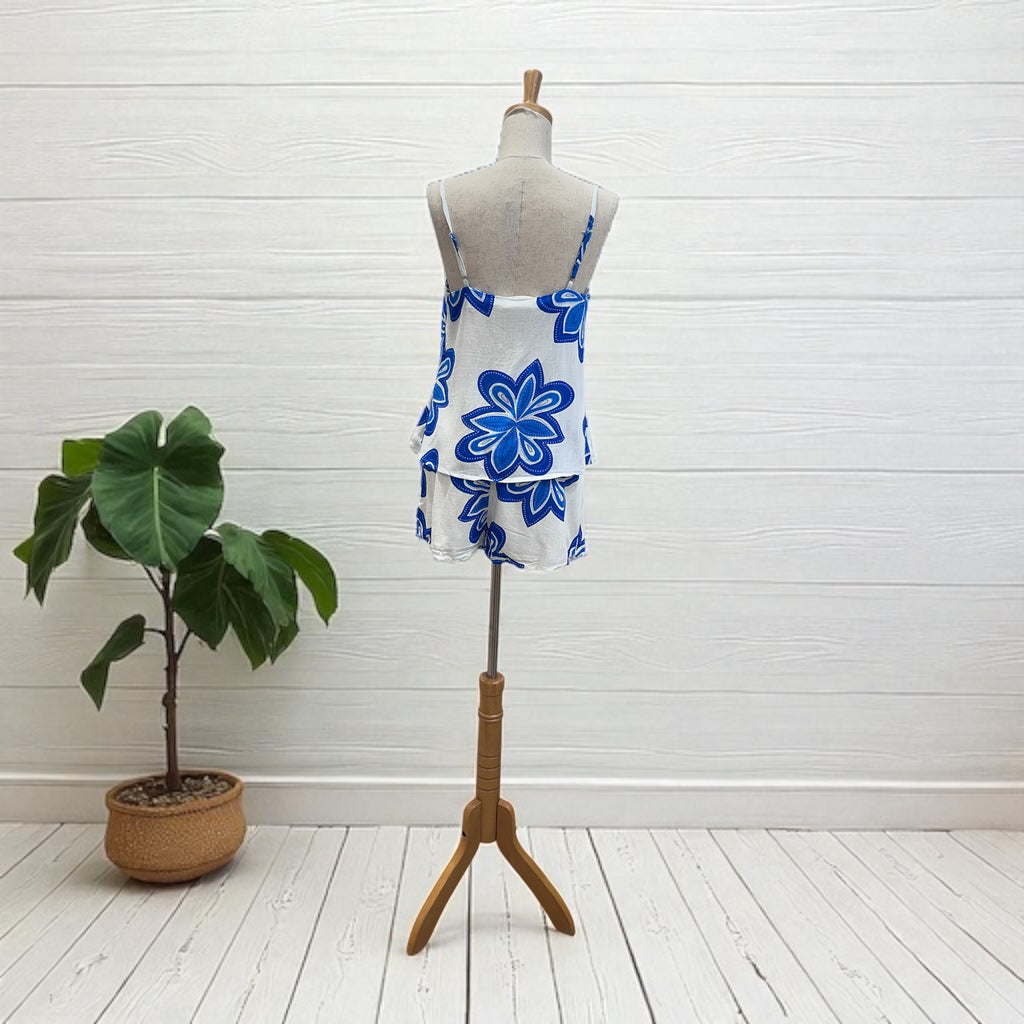 Mannequin wearing a blue and white floral dress next to a potted plant on a white floor.