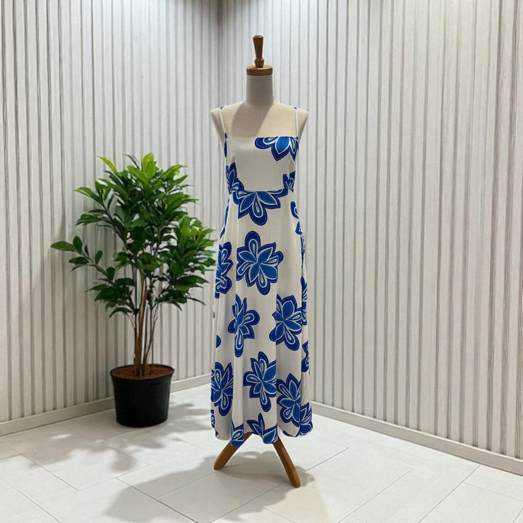 Mannequin wearing a white dress with blue floral patterns against a striped wall.