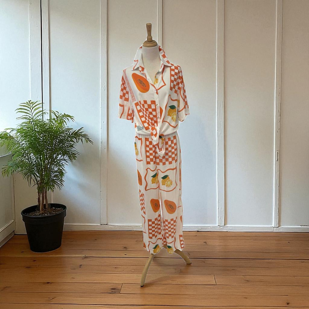 Vintage-style outfit with orange and white pattern on a mannequin against a white paneled wall.