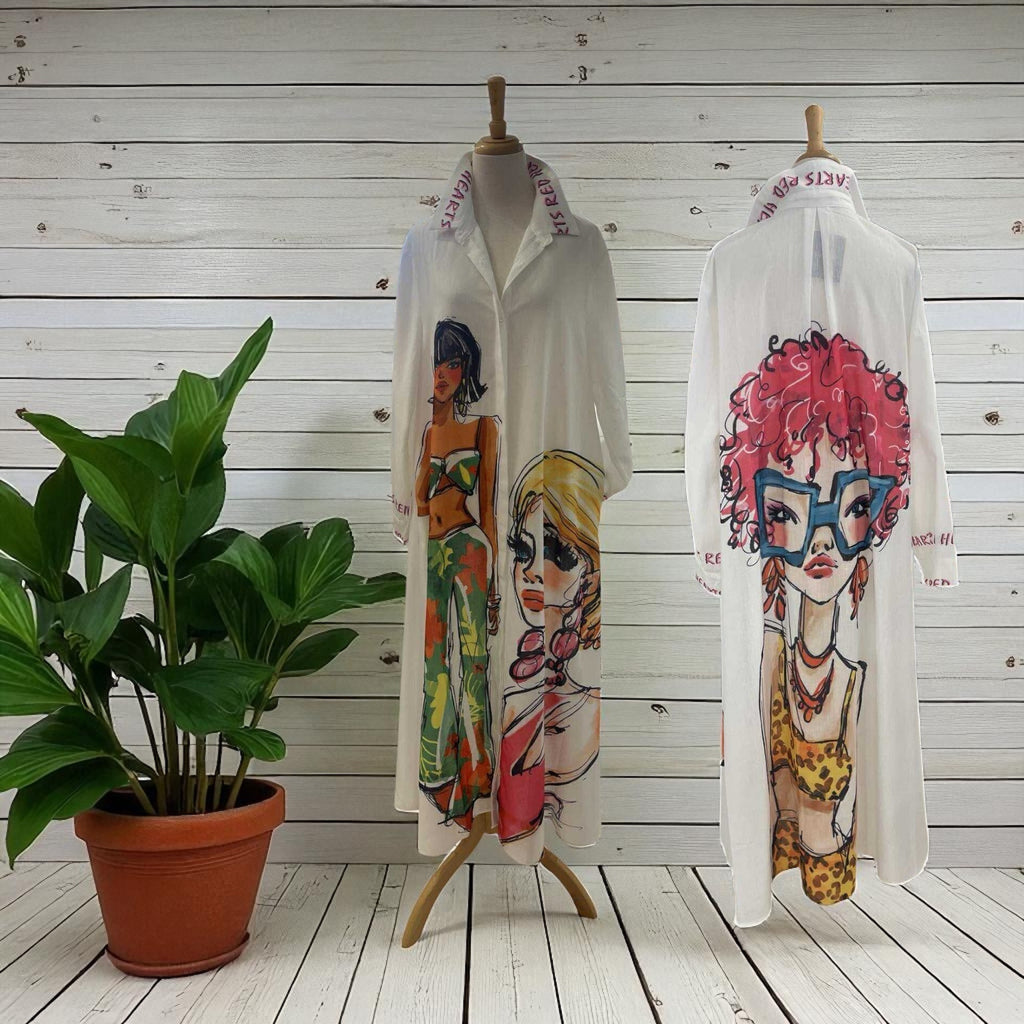Two mannequins wearing white shirts with colorful graphic designs on a wooden floor with a plant.