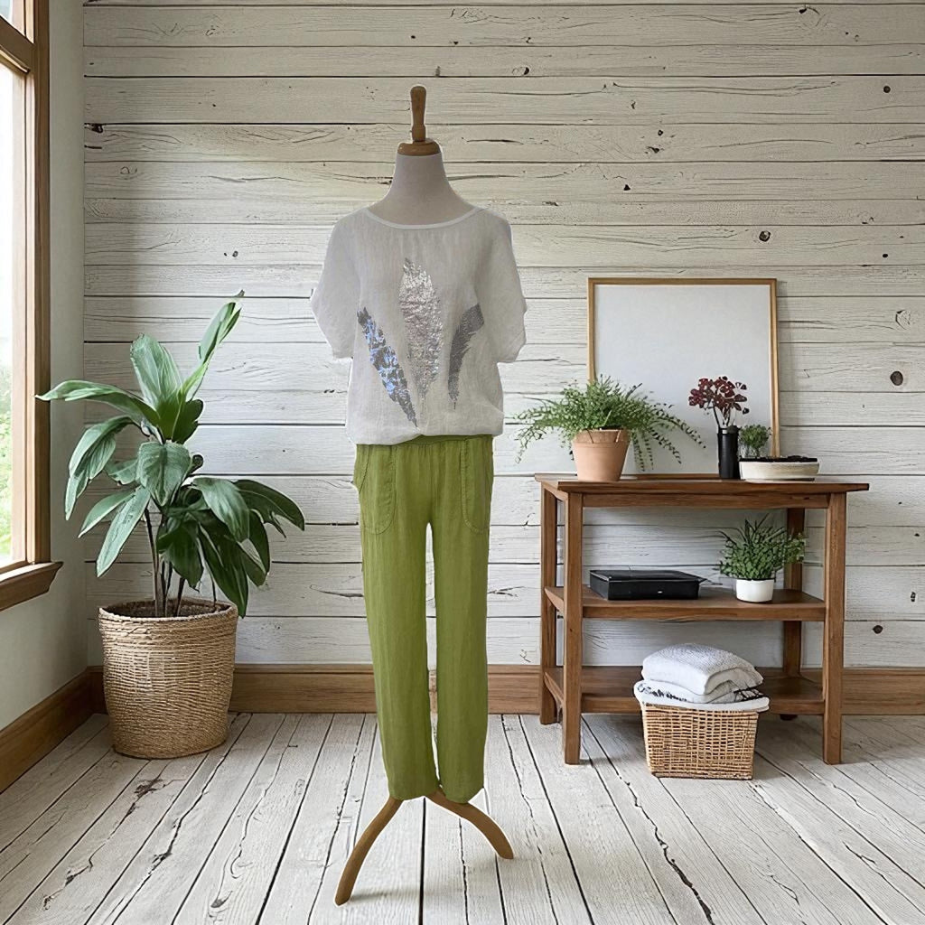 Mannequin wearing a white top and green pants in a room with wooden floor and wall.
