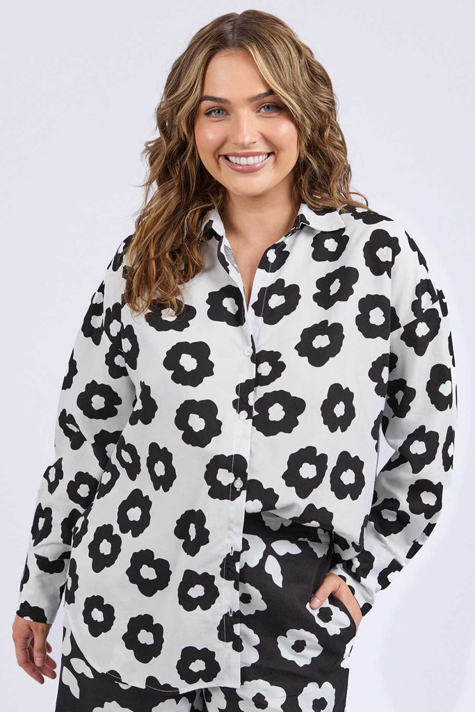 Woman wearing a black and white floral patterned shirt on a white background