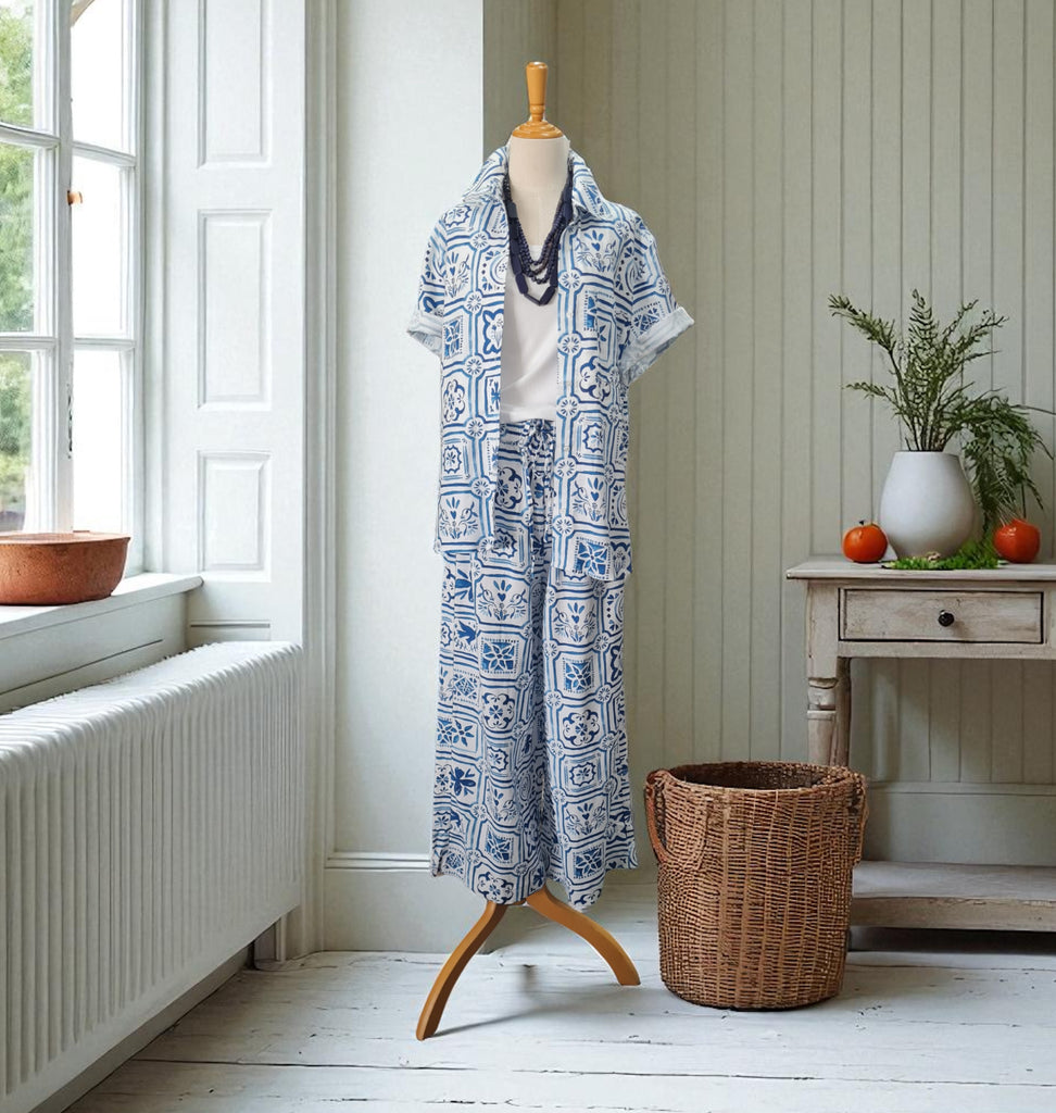 Mannequin wearing a blue and white patterned outfit in a room with a window and wooden furniture.